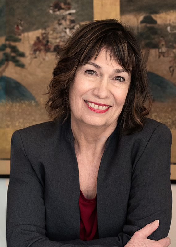 Leslie Davenport - a person with shoulder length hair is wearing a blazer and top and smiling at the camera.