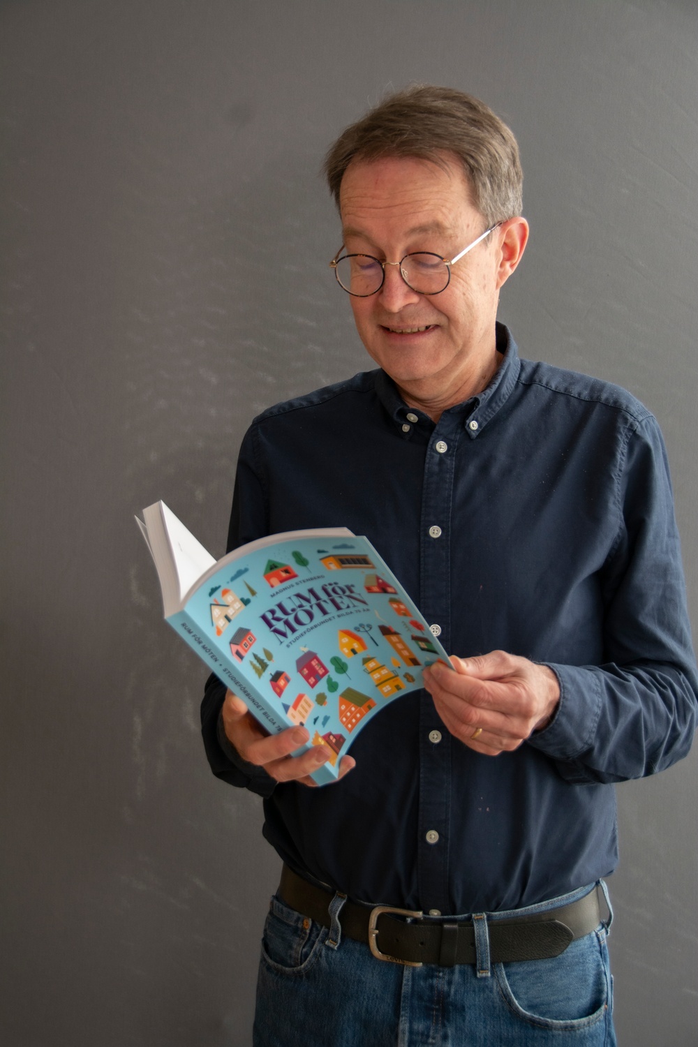 Magnus Stenberg, författare till Bildas jubileumsbok "Rum för möten", står och bläddrar i boken.
