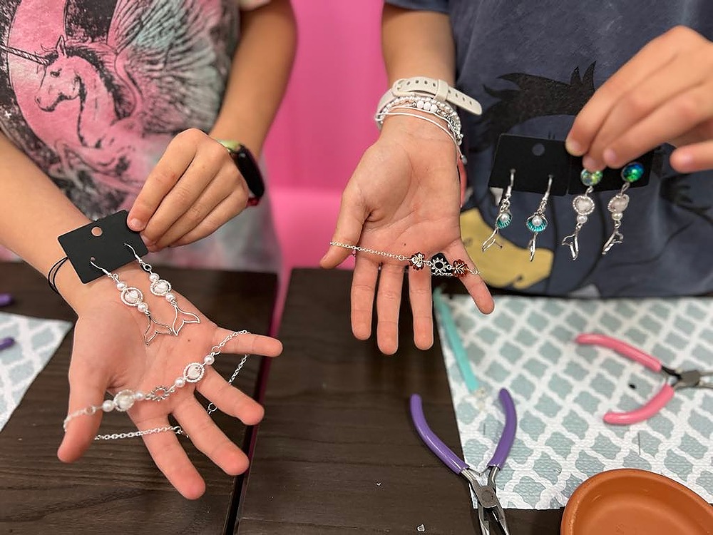 Hands showing jewellery pieces make. 3 x earrings pairs and 2 x charm bracelets