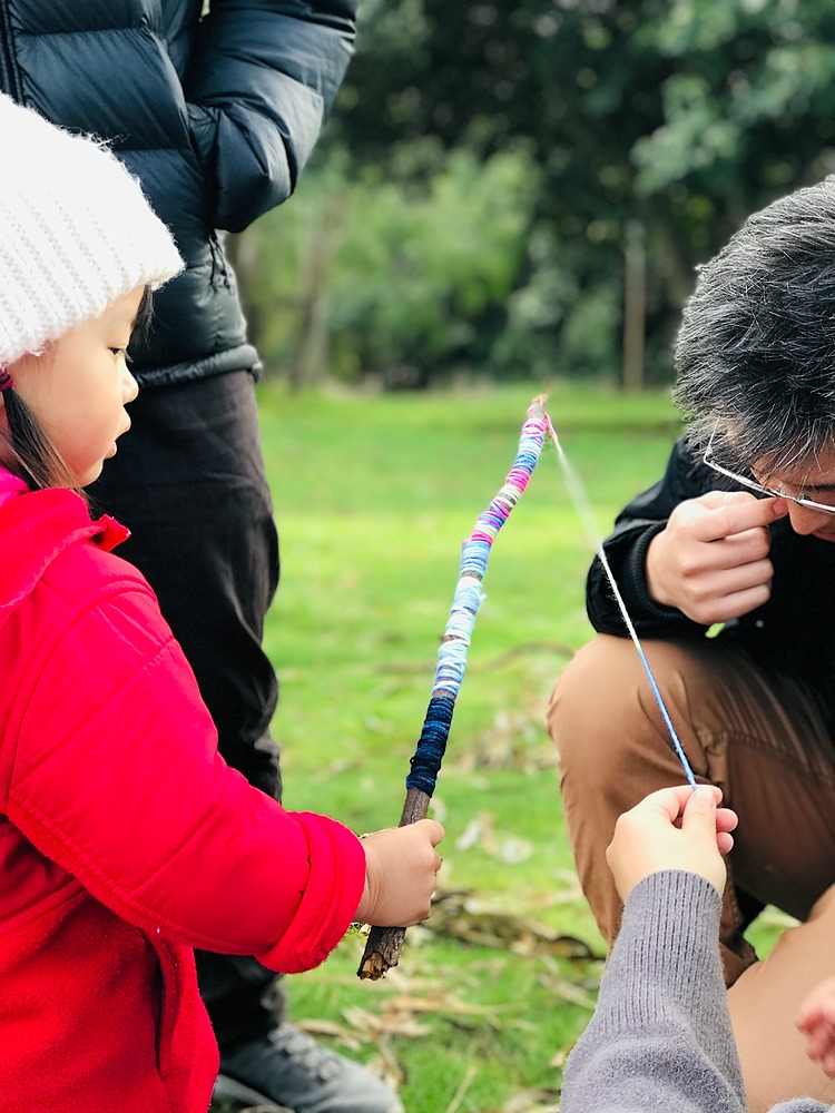 Child holding message stick with colourful wool