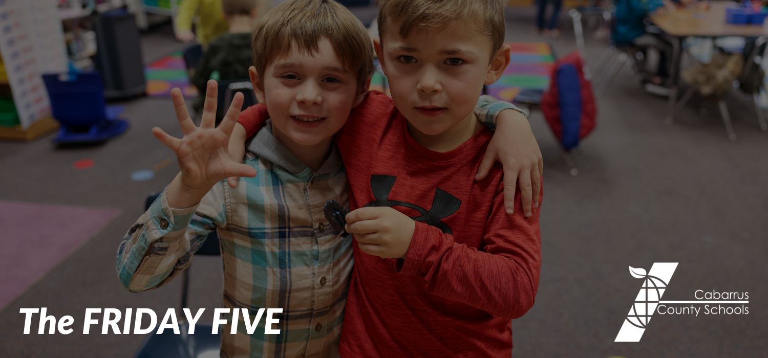 Two students holding up five fingers.