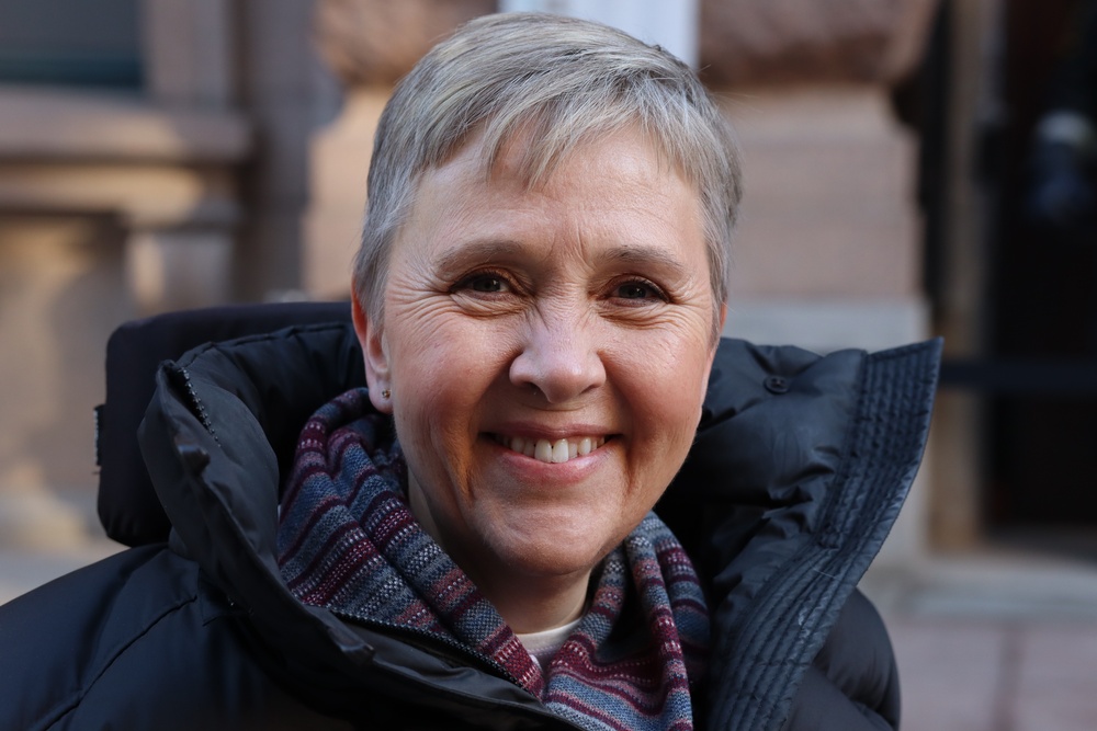 Lise Lidbäck ler på bild utanför riksdagshuset i Stockholm.