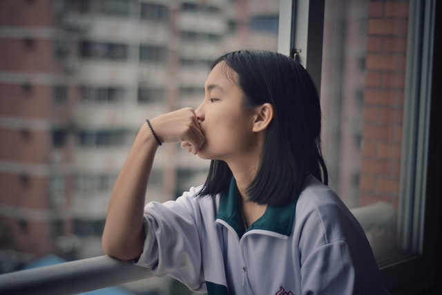 A girl watching outside the window, alone without her couple