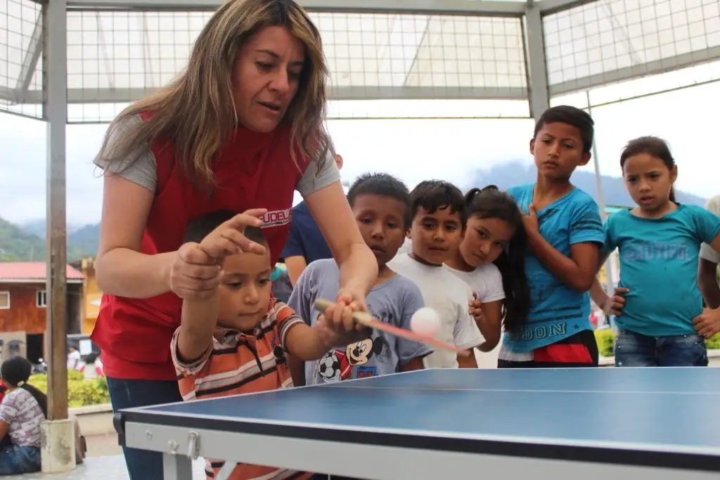 Promotora de FUDELA enseñando a niños a jugar ping pong