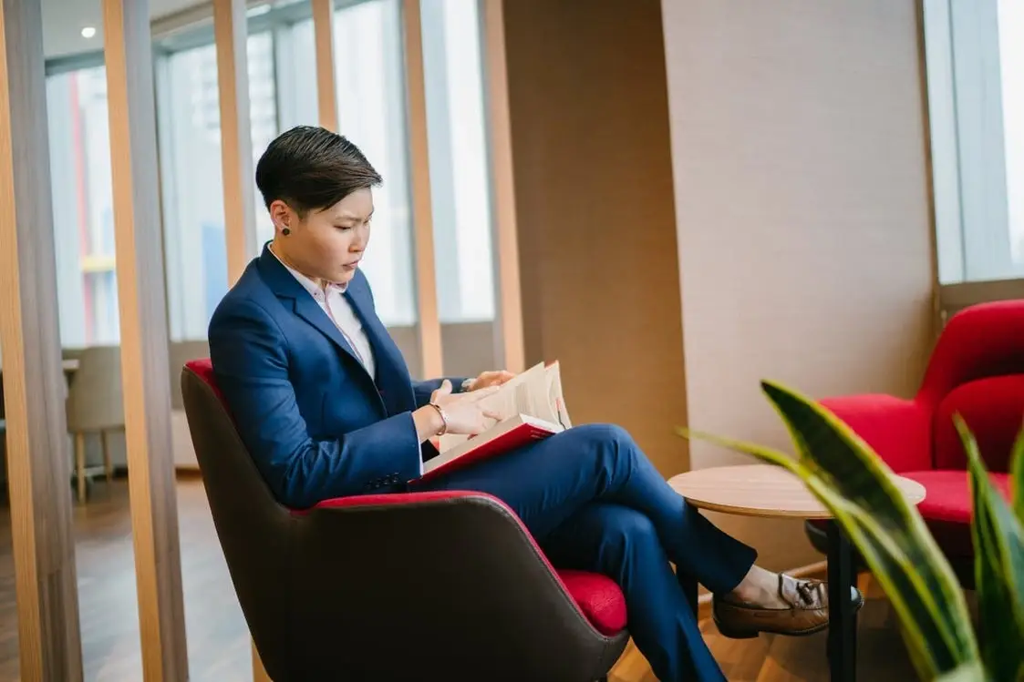 Someone sitting and reading a book in a suit