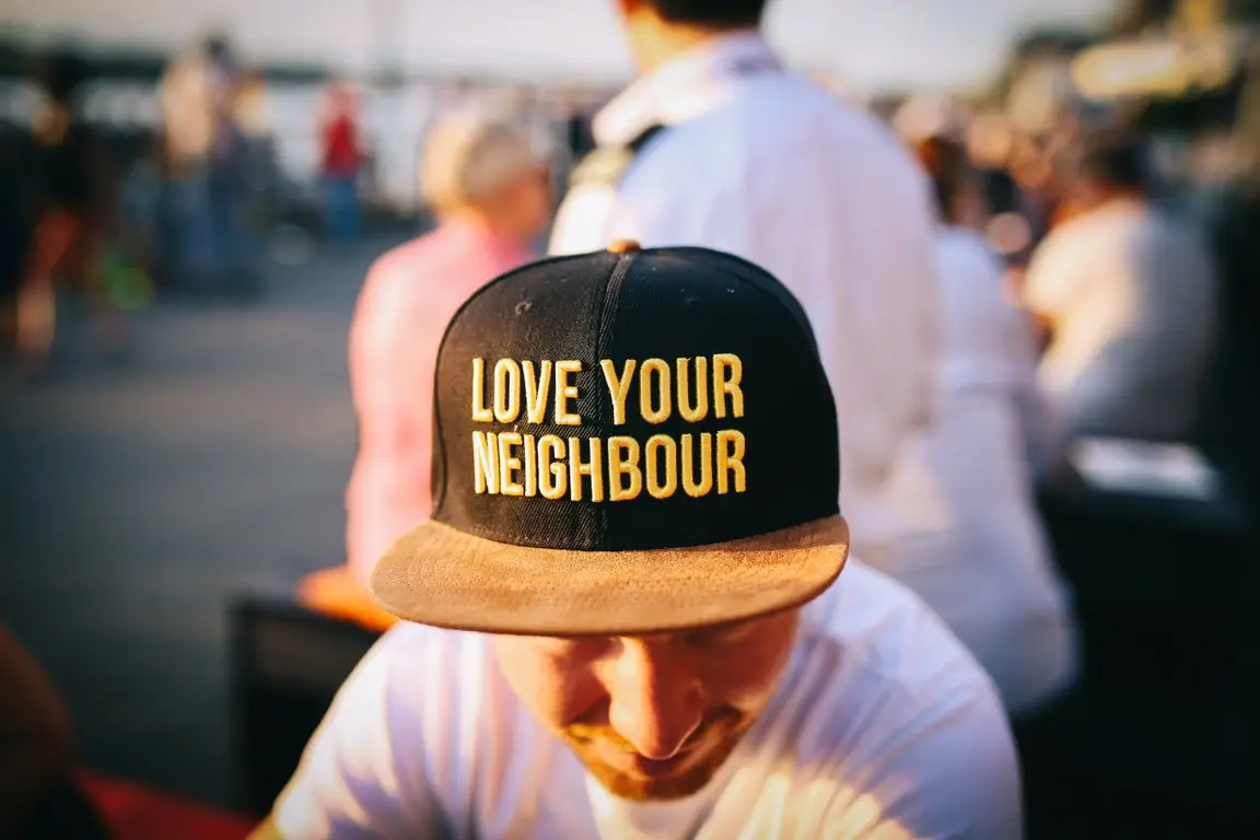 Rapaz com boné com os dizeres "Love Your Neighbor" (Ama o teu próximo, em português)
