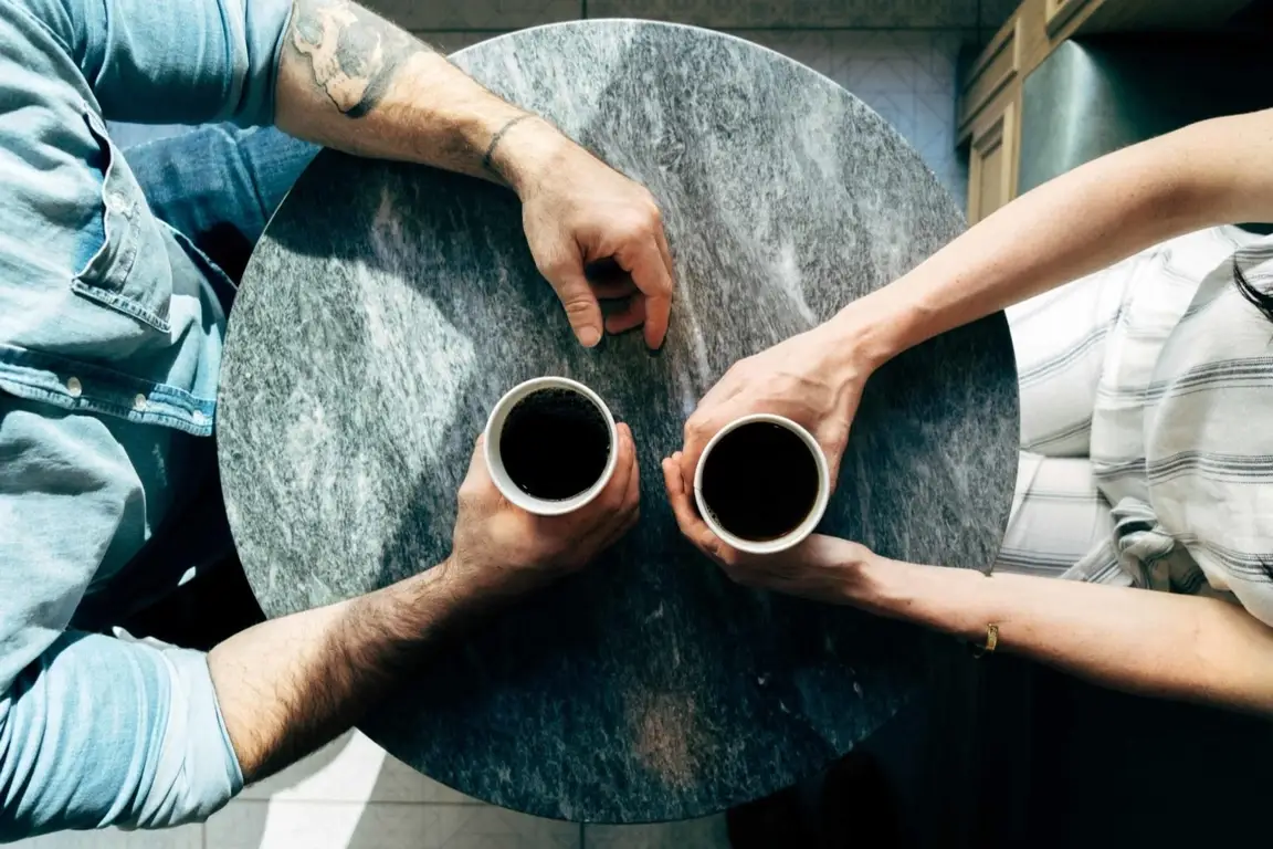 Two people sitting with a cup of coffee.