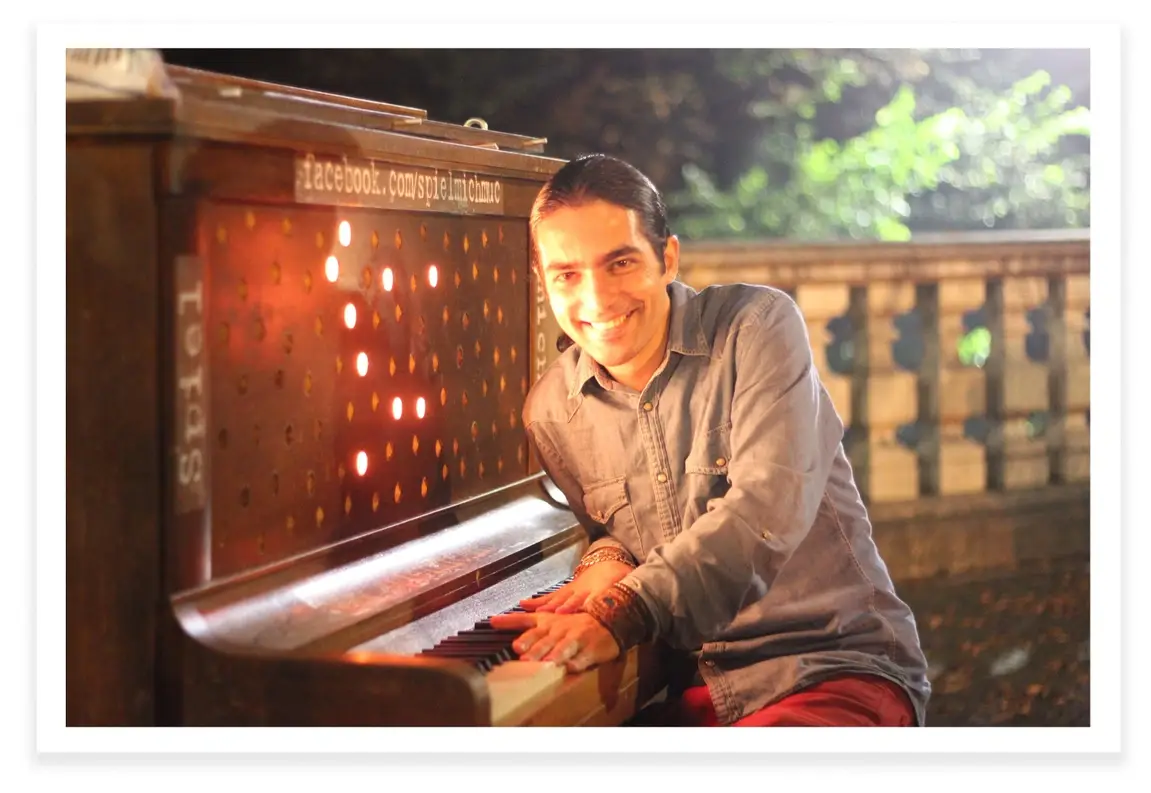Fabio Tedde sits at a piano smiling at the camera.