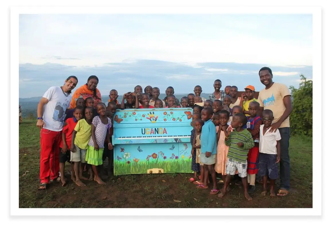 Fabio Tedde poses with a group of children around a blue piano.