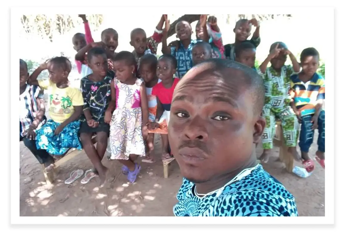 Francis Osei takes a selfie with a group of school children behind him.