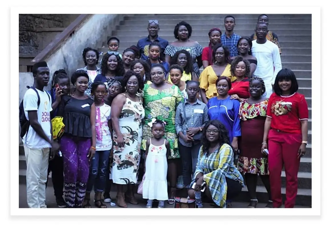 Elizabeth Brewah poses for a photo with a group of people in front of stairs.