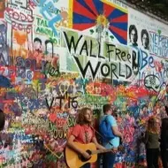 Cantora tocando violão na frente de uma parede cheia de grafites
