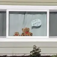 A window with two teddybears in it, one with a speech bubble next to it that says, "Happy hunting."