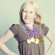 Uma garota com várias medalhas de ouro penduradas no pescoço