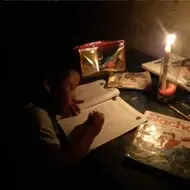 Uma criança estudando à luz de velas
