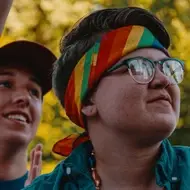 Two people with rainbow bandana smiling, image for Idealist's blog post 3 Things to Keep in Mind When You Come Out at Work