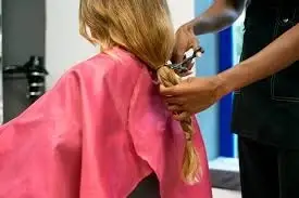 Hairstylist cutting woman's braid.