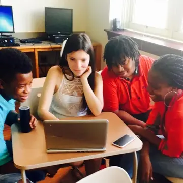 3 teen writers with their story coach looking at a computer