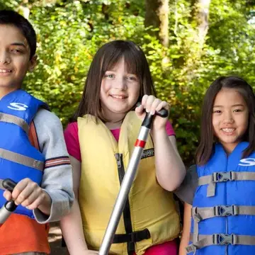 Summer camp youth wearing life preservers and holding oars
