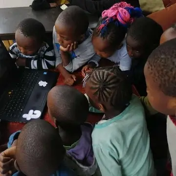 Children looking at the laptop of our visitor