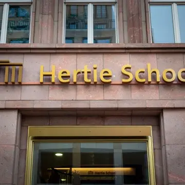Hertie School sign on pink building facade.