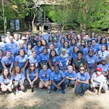 a large group of students in matching blue Trachtenberg tshirts pose for a photo
