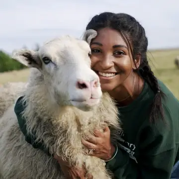 Farm Sanctuary staff, Arianna Duncan, poses with Adriano Sheep