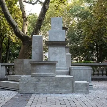 A series of gray concrete plinths of varying shapes and sizes, stacked upon each other in a pile