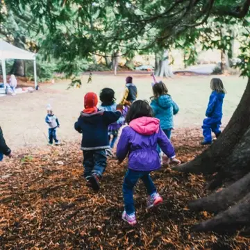 Students running and playing in forest classroom.
