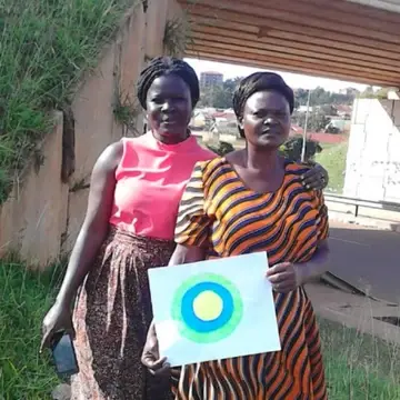 Two women pose with the Idealist logo between them.