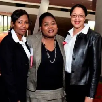 Three Black women posing for a photo with their arms around each other inside the Georgia World Congress Center.