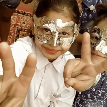two small girls wearing silver masks after art performance at Sewing New Futures' play area in New Delhi