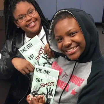 two teen authors pose with proof copies of their book