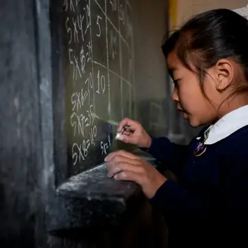 Tibetan refugee girl writing on chalkboard