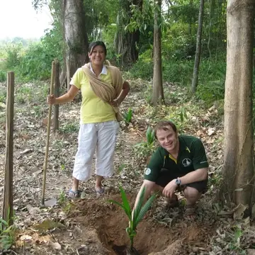 two people planting a tree in the ground