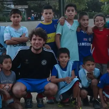 Volunteer with many children at football workshop