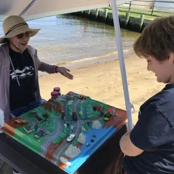 woman in water spirit shirt explains storm water management to a kid by using an enviroscape