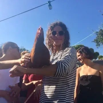 Man in sunglasses holding a chicken.