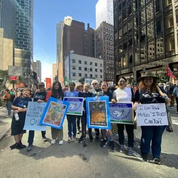 Water spirit group poses with signs protesting fossil fuels in New York City at the March to End Fossil Fuels