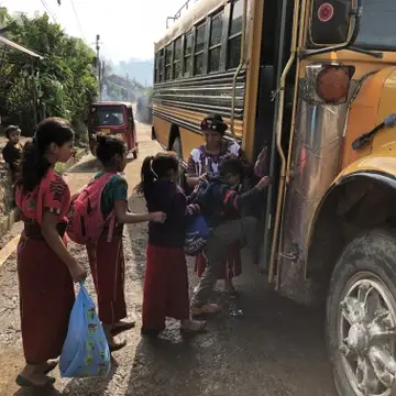 children in Guatemala get on a schoolbus