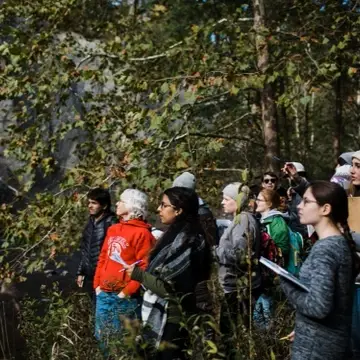 Group of students and faculty exploring an outdoor space near a waterfall