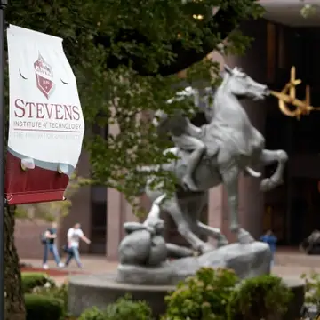 Stevens banner in the foreground with Torchbearer Sculpture in background