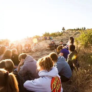Youth volunteers at an evening program in Chiloquin, OR sit on a bluff at sunset overlooking Klamath Lake.