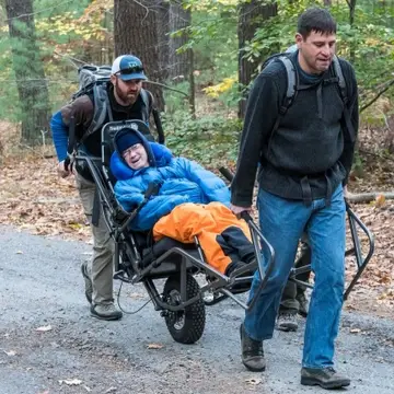 Two Waypoint volunteers pushing and pulling a Waypoint participant on a hiking program.