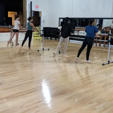 Students at the barre with one foot pointed behind them.