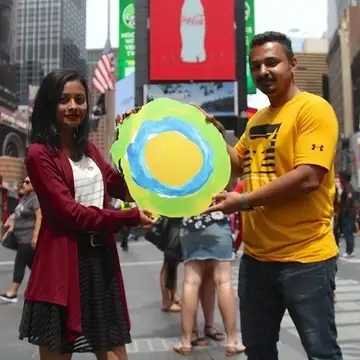 Two people hold up the Idealist logo.