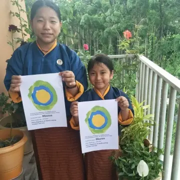 Two children pose with the Idealist logo in Bhutan.