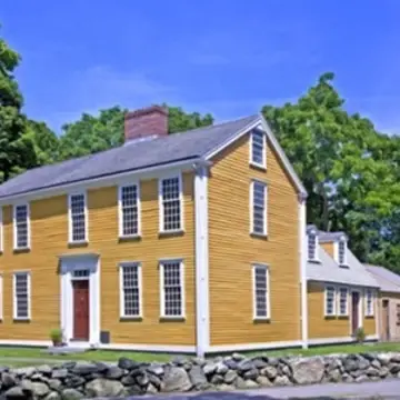 Yellow, colonial-era, two-story building with additions at back