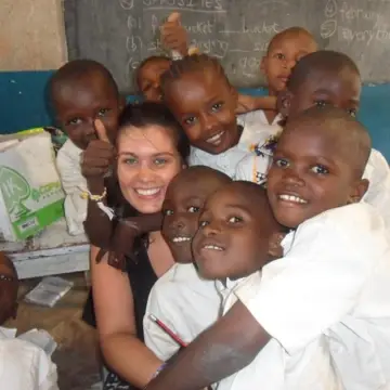 Children smiling around a volunteer in a classroom