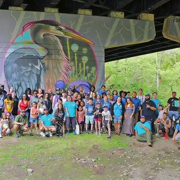 Participants gather under the Great Blue Heron mural in Tacony Creek Park during TTF's "Birds of a Feather" art festival
